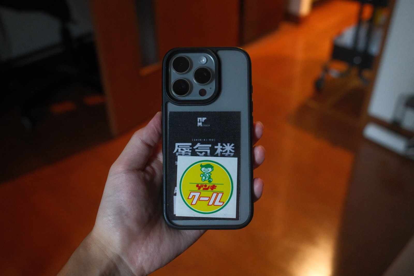 NIMASOのクリアケースを付けたiPhoneを手に持った写真。背面にステッカーを貼っている